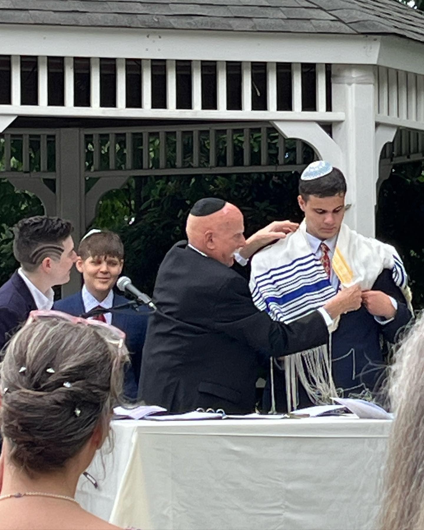 Marshall helping a young family member with a tallit during a family ceremony